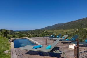 a row of lounge chairs sitting on a deck next to a pool at Bergerie face à Propriano in Fozzano