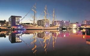 a large boat sitting on the water in a city at Schulschiff Deutschland Bremerhaven in Bremerhaven