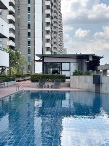 a swimming pool with two chairs in front of a building at Bann-Kun Impact Muang Thong 2BR Condo Wi-Fi MRT Pink Near Airport DM in Nonthaburi