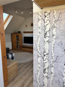 a living room with a wall mural of trees at Pioppo Apartman in Tiszavasvári +3 photos