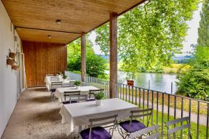 a patio with tables and chairs and a river at Hôtel Domaine de la Sauge in Cudrefin