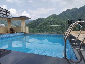 a swimming pool with mountains in the background at Foxoso Heights, Tapovan in Rishīkesh