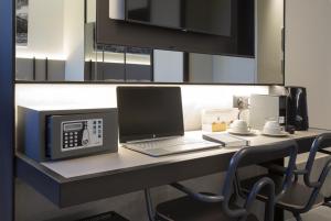 a laptop computer sitting on a desk with a microwave at CUBIK inn Design Rooms in Gravina di Catania