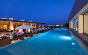a hotel swimming pool with chairs and umbrellas at night at Radisson Blu Hotel & Convention Center, Tunis in Tunis