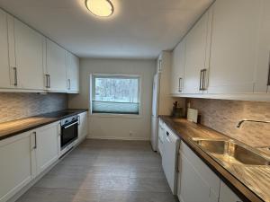 a kitchen with white cabinets and a sink and a window at Spacious apartment in Follebu in Aulestad