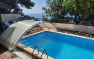 a swimming pool with an umbrella over it at Apartments Rose in Stanići
