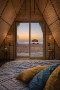 a bedroom with a view of the beach from a window at Sukoon Nuweibaa in Nuweiba