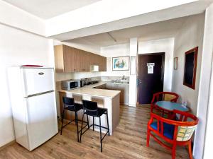 a kitchen with a white refrigerator and red chairs at Petalmo City Apartments in Larnaca