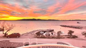 a sunset over a body of water with a car at Luxury Beach Villa, Sibenik in Šibenik