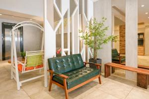a green leather chair in a lobby with a table at A Hotel Joo Chiat in Singapore