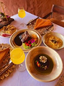 a table with plates of food and glasses of orange juice at Mekong Silt Ecolodge - Swimming Pool & Free Breakfast in Can Tho