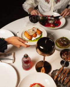 a table with plates of food and a person holding a plate of food at Unfound Door - Design Hotel in Tbilisi City