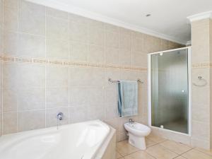 a bathroom with a bath tub and a toilet at Coney Glen Penthouse in Knysna +34 photos