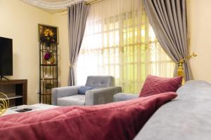 a living room with a couch and chairs and a window at JANNAH VILLAS - GHANA in Adentan