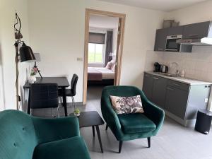 a living room with a green chair and a kitchen at 't lant van Texsel in De Koog