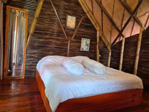 a bedroom with a bed with white sheets and pillows at Villa Bambu Juma & Bakal in Kotasuka