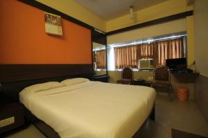 a bedroom with a large white bed with orange walls at HOTEL GOLDEN PALACE PVT LTD in Mumbai