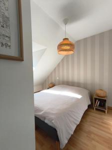 a bedroom with a white bed and a chandelier at Superbe duplex « le Grévy » in Dole