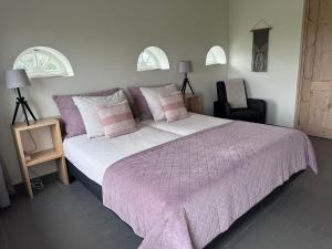 a bedroom with a large bed with a purple blanket at 't lant van Texsel in De Koog