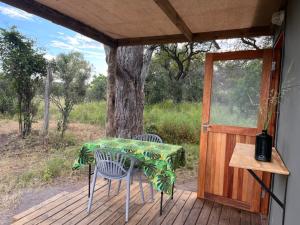 a table and chairs on a porch with a door at The Termite Mound - Termite Tented in Khwai