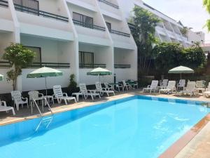 a hotel with a swimming pool and chairs and umbrellas at Sirin Hotel Hua Hin in Hua Hin