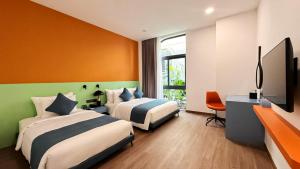 a hotel room with two beds and a flat screen tv at Amigo Sol Phan Thiet in Phan Thiet