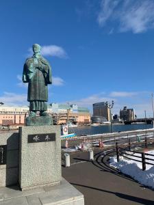 a statue of a man standing next to the water at 釧路の夕日に近い宿トラベラーズイン南大通 in Kushiro