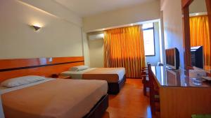 a hotel room with two beds and a television at Paradise Hotel in Tanjung Pinang