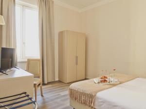 a bedroom with a bed and a desk and a cabinet at Hotel L'Aretino in Arezzo