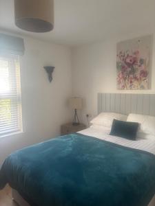 a bedroom with a bed with a blue blanket on it at Racecourse View in Listowel