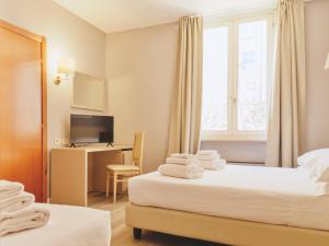 a hotel room with two beds and a desk at Hotel L'Aretino in Arezzo