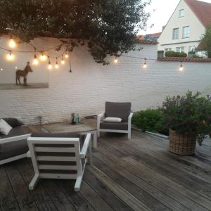 a patio with a couch and a chair and lights at b&b les invités in Bruges