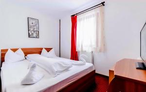 a bedroom with two beds and a desk and a window at Pensiunea Vacanta in Straja