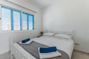 a white bedroom with a white bed and a window at Beach Escape Beachfront Apartment in Pyla