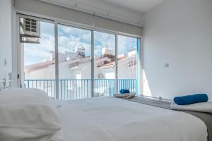 a white bed in a room with a large window at Beach Escape Beachfront Apartment in Pyla