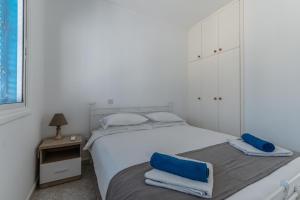 a white bedroom with two beds and a night stand at Beach Escape Beachfront Apartment in Pyla +12 photos