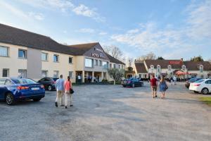 a group of people walking through a parking lot at Hotel The Originals Bernay Acropole in Bernay