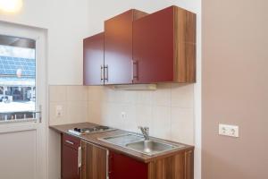 a kitchen with a sink and wooden cabinets at Apartmentdorf Flößerstube in Grossraming +35 photos