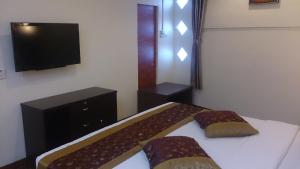 a bedroom with a bed and a flat screen tv at Hotel & Apartment Ambassador 3 in Labuan
