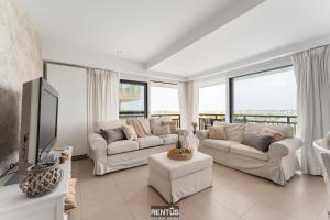 a living room with white furniture and large windows at Seange - with beautiful view and many facilities in Nieuwpoort