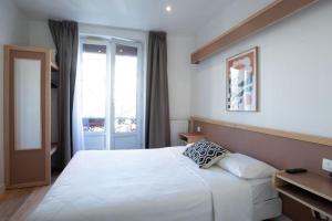 a bedroom with a large white bed and a window at Hôtel Edgar Quinet in Paris