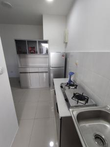 a small kitchen with a sink and a stove at Halimah Guesthouse in Putatan