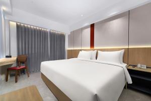 a bedroom with a large white bed and a desk at MAXONE Batam in Nagoya