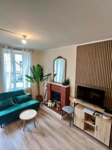 a living room with a green couch and a television at Maison de la Gour MELLE in Melle
