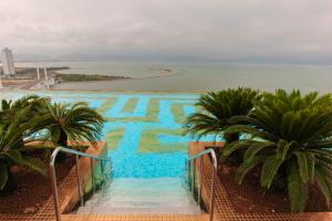 a view of a swimming pool with palm trees and the ocean at Golden Bay Danang in Danang +6 photos