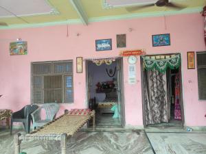 a room with a pink wall with a bench in it at Dheeraj Kumar Homestay in Phalauda