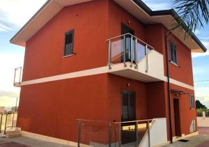 a red building with a balcony on the side of it at Casa Decastadio in Melito di Porto Salvo