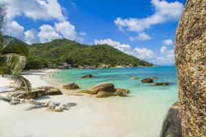 a beach with rocks and the ocean with people on it at Crystal Bay Yacht Club Beach Resort in Lamai