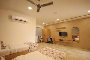 a hotel room with two beds and a tv at Taste Carnival in Vadodara