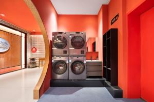 a laundry room with two washing machines and an orange wall at Beijing TangFu Chinese Culture Boutique Hotel Sanlitun Embassy Area in Beijing